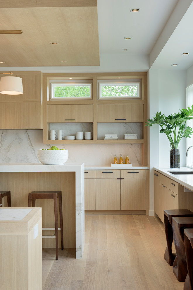 Exempel på ett stort modernt kök med öppen planlösning, med en undermonterad diskho, släta luckor, skåp i ljust trä, marmorbänkskiva, vitt stänkskydd, stänkskydd i sten, integrerade vitvaror, ljust trägolv och flera köksöar
