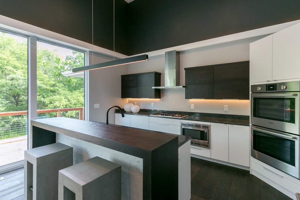 Large contemporary l-shaped open plan kitchen in Cedar Rapids with a submerged sink, flat-panel cabinets, dark wood cabinets, granite worktops, stainless steel appliances and an island.
