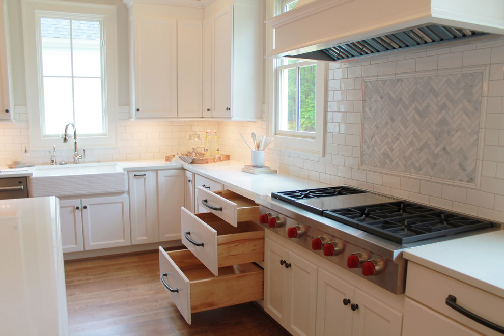 Idéer för att renovera ett mycket stort vintage kök, med en rustik diskho, släta luckor, vita skåp, bänkskiva i kvarts, vitt stänkskydd, stänkskydd i stenkakel, integrerade vitvaror, mellanmörkt trägolv och en köksö