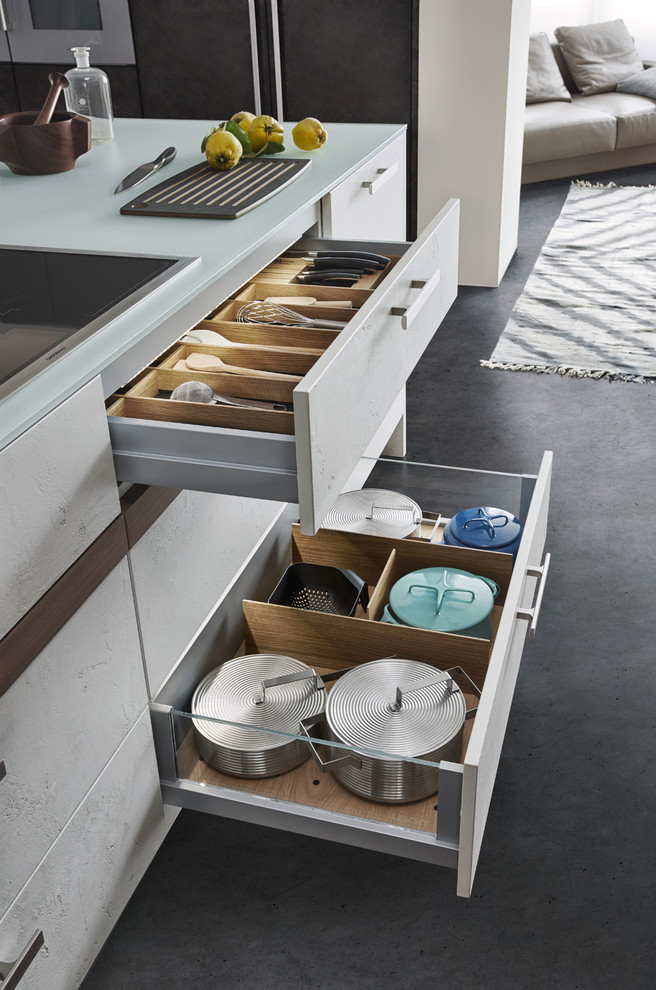 Esempio di una cucina minimalista di medie dimensioni con ante lisce, ante grigie, top in superficie solida, paraspruzzi bianco, elettrodomestici in acciaio inossidabile, pavimento in cemento e lavello da incasso