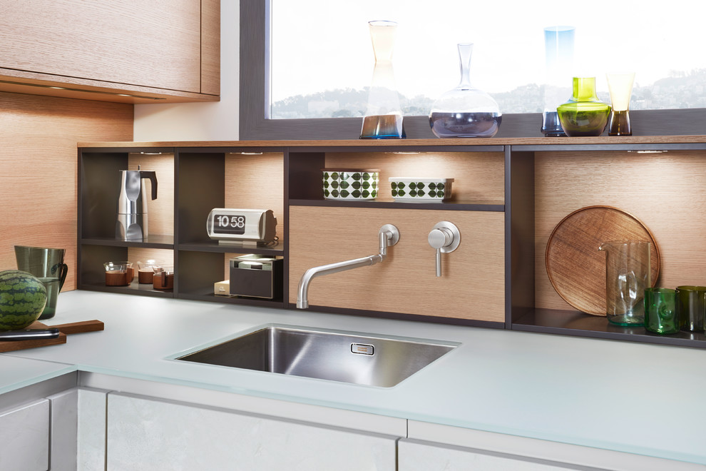 Exempel på ett mellanstort modernt kök, med en undermonterad diskho, släta luckor, vita skåp, bänkskiva i glas, rostfria vitvaror, betonggolv och en köksö