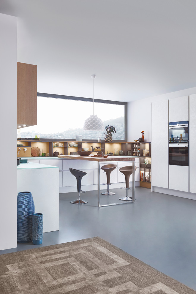 Foto på ett mellanstort funkis kök, med en undermonterad diskho, släta luckor, vita skåp, bänkskiva i glas, rostfria vitvaror, betonggolv och en köksö
