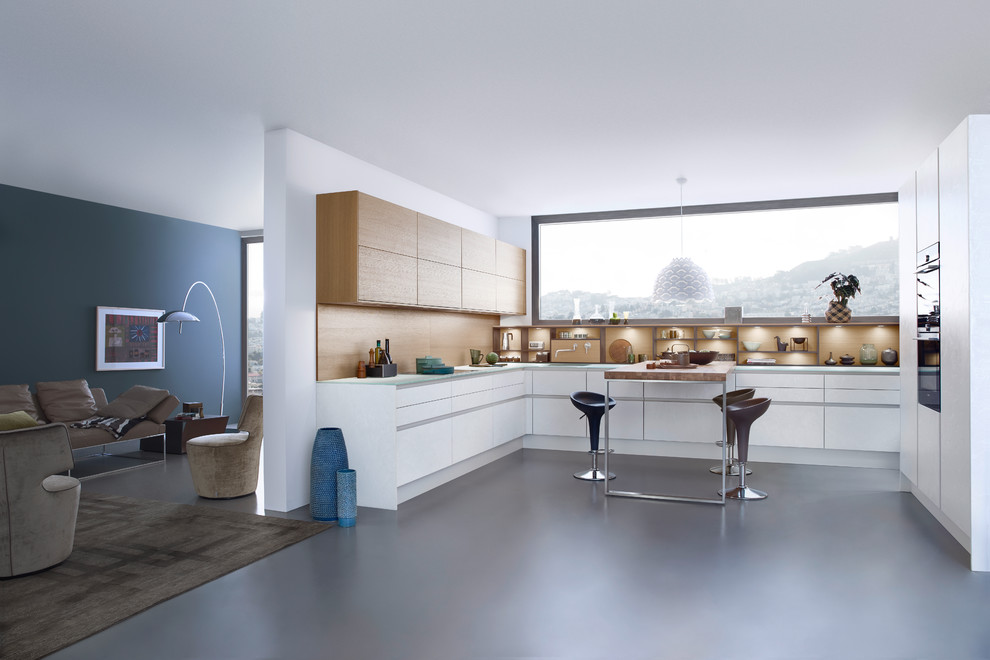 На фото: параллельная кухня-гостиная среднего размера в стиле модернизм с врезной мойкой, плоскими фасадами, белыми фасадами, стеклянной столешницей, техникой из нержавеющей стали, бетонным полом и островом с