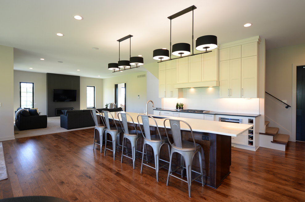Inspiration for a large transitional single-wall medium tone wood floor open concept kitchen remodel in Other with an undermount sink, recessed-panel cabinets, white cabinets, granite countertops, white backsplash, stainless steel appliances and an island