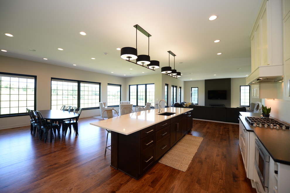 Example of a large transitional single-wall medium tone wood floor open concept kitchen design in Other with an undermount sink, recessed-panel cabinets, white cabinets, granite countertops, white backsplash, stainless steel appliances and an island