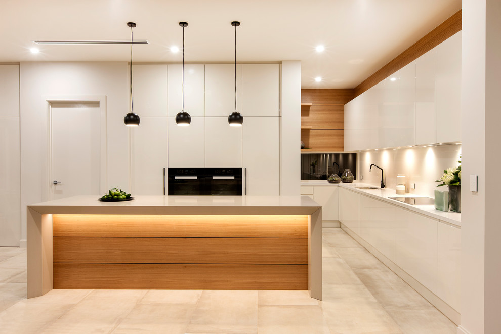 Große Moderne Küche in L-Form mit flächenbündigen Schrankfronten, weißen Schränken, Küchenrückwand in Weiß, Glasrückwand, schwarzen Elektrogeräten, Kücheninsel und beigem Boden in Adelaide