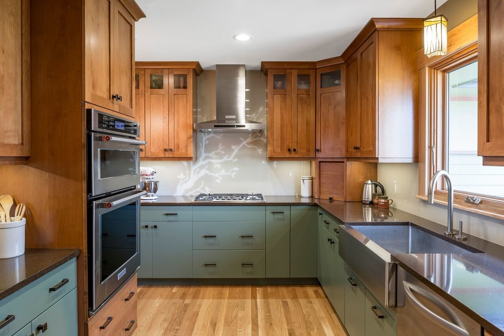 Photo of a large rustic galley enclosed kitchen in Minneapolis with a belfast sink, shaker cabinets, medium wood cabinets, grey splashback, stainless steel appliances, light hardwood flooring and no island.