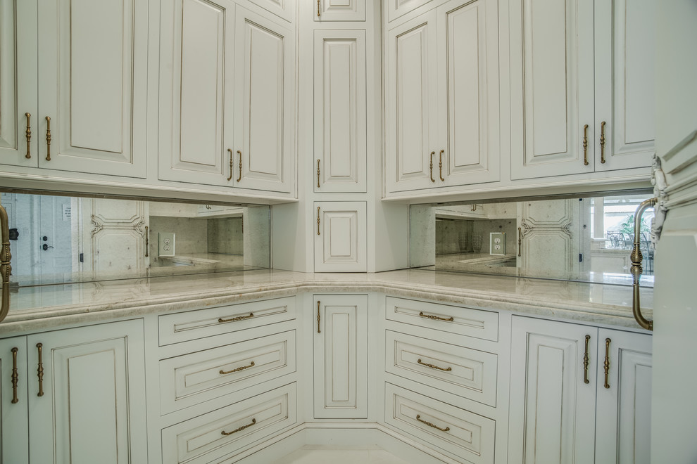 Klassisk inredning av ett stort l-kök, med en rustik diskho, luckor med upphöjd panel, vita skåp, marmorbänkskiva, vitt stänkskydd, stänkskydd i stenkakel och en köksö