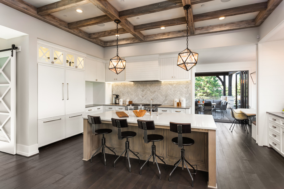 Exempel på ett klassiskt l-kök, med en undermonterad diskho, vita skåp, vitt stänkskydd, stänkskydd i marmor, rostfria vitvaror, mörkt trägolv, en köksö och brunt golv