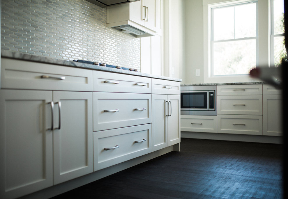 Foto på ett funkis kök, med skåp i shakerstil, vita skåp, granitbänkskiva, rostfria vitvaror och en köksö