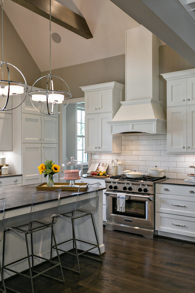 Inspiration for a large transitional l-shaped dark wood floor kitchen remodel in Birmingham with a farmhouse sink, shaker cabinets, white cabinets, quartzite countertops, white backsplash, stainless steel appliances, an island and subway tile backsplash