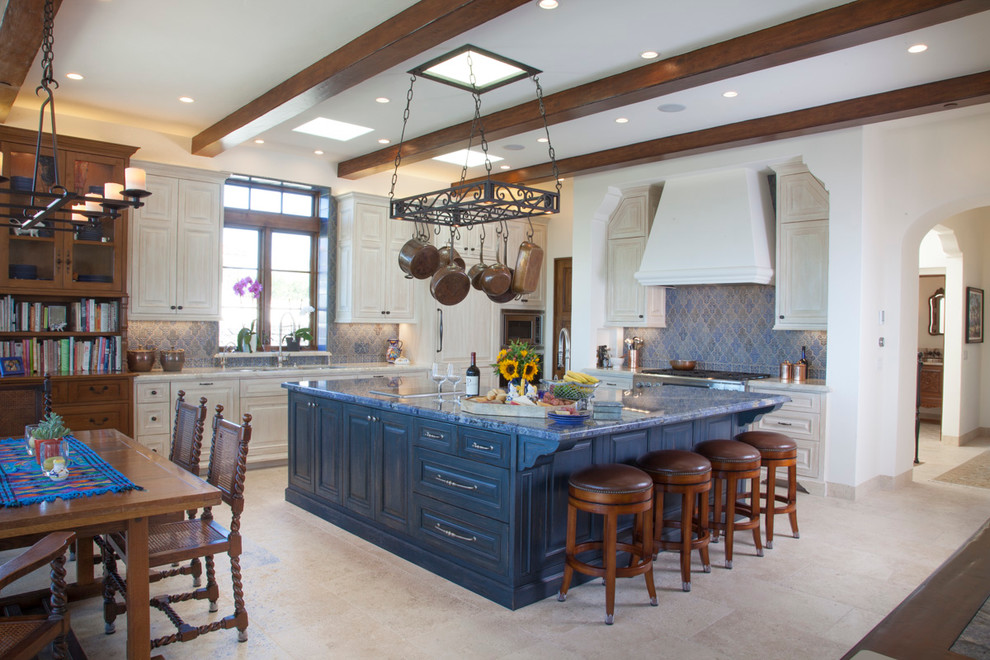 Inredning av ett medelhavsstil stort kök, med luckor med upphöjd panel, beige skåp, blått stänkskydd, en köksö, en nedsänkt diskho, bänkskiva i kvarts, stänkskydd i keramik, rostfria vitvaror och travertin golv