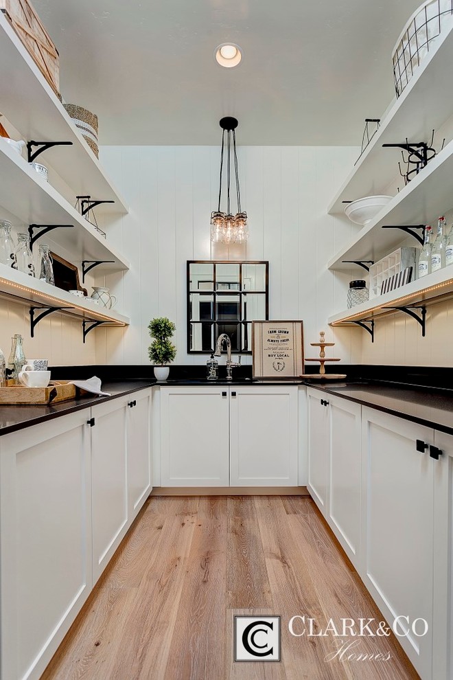 Inspiration for a large country u-shaped light wood floor kitchen pantry remodel in Boise with an undermount sink, shaker cabinets, white cabinets, quartz countertops, white backsplash, wood backsplash and no island