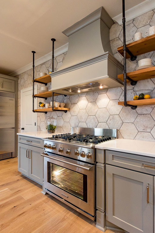 Inspiration for a mid-sized transitional l-shaped light wood floor eat-in kitchen remodel in Nashville with a farmhouse sink, shaker cabinets, gray cabinets, quartz countertops, brown backsplash, ceramic backsplash, stainless steel appliances and an island