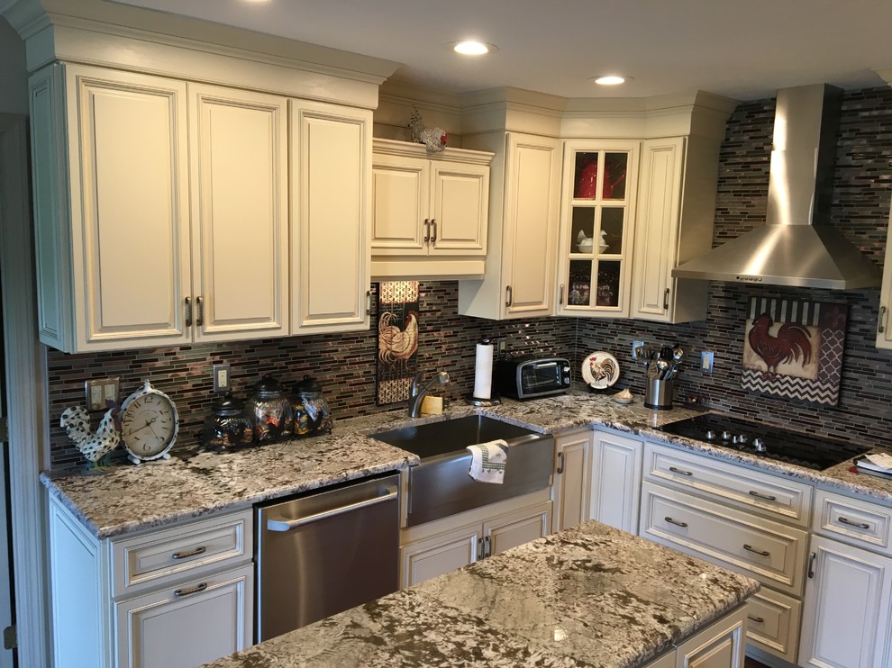Example of a mid-sized classic u-shaped medium tone wood floor and brown floor eat-in kitchen design in Louisville with a farmhouse sink, raised-panel cabinets, white cabinets, granite countertops, brown backsplash, glass tile backsplash, stainless steel appliances and an island
