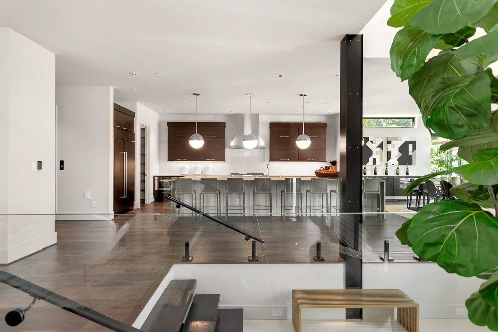 This is an example of a large contemporary single-wall kitchen/diner in Seattle with a submerged sink, flat-panel cabinets, dark wood cabinets, concrete worktops, white splashback, stainless steel appliances, dark hardwood flooring, an island and brown floors.