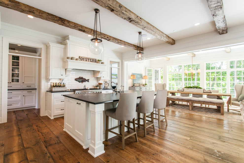 Inspiration for a cottage galley medium tone wood floor and brown floor open concept kitchen remodel with white cabinets, granite countertops, white backsplash, stainless steel appliances, an island, shaker cabinets, subway tile backsplash and black countertops