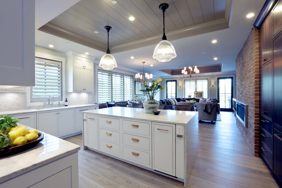 На фото: параллельная кухня-гостиная среднего размера в стиле модернизм с накладной мойкой, белыми фасадами, белым фартуком, светлым паркетным полом, островом и коричневым полом с