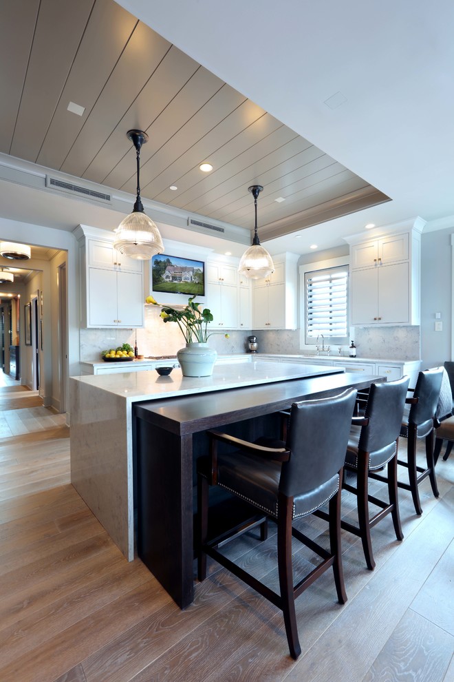 На фото: параллельная кухня-гостиная среднего размера в стиле модернизм с накладной мойкой, белыми фасадами, белым фартуком, светлым паркетным полом, островом и коричневым полом с