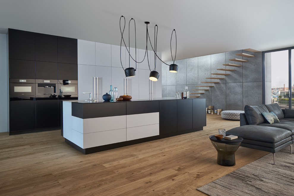 Esempio di un'ampia cucina moderna con ante lisce, ante nere, lavello sottopiano, top in superficie solida, elettrodomestici neri e parquet chiaro