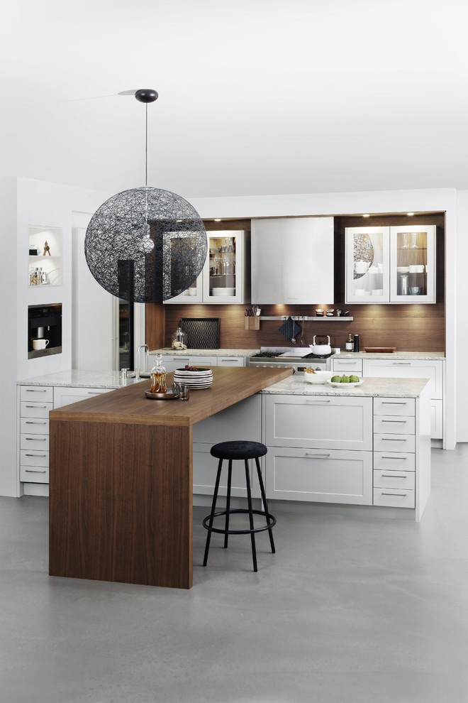 Inspiration for a large modern l-shaped kitchen/diner in New York with a belfast sink, shaker cabinets, white cabinets, laminate countertops, brown splashback, stainless steel appliances, concrete flooring and a breakfast bar.