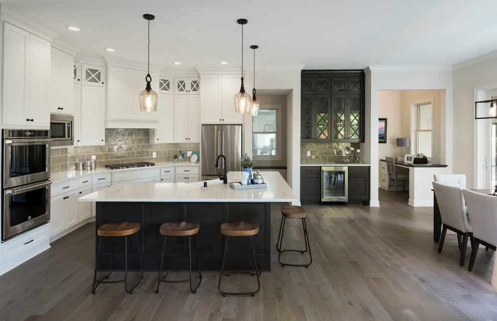 This is an example of a traditional kitchen/diner in Minneapolis with a submerged sink, shaker cabinets, grey splashback, stainless steel appliances, medium hardwood flooring, an island and brown floors.