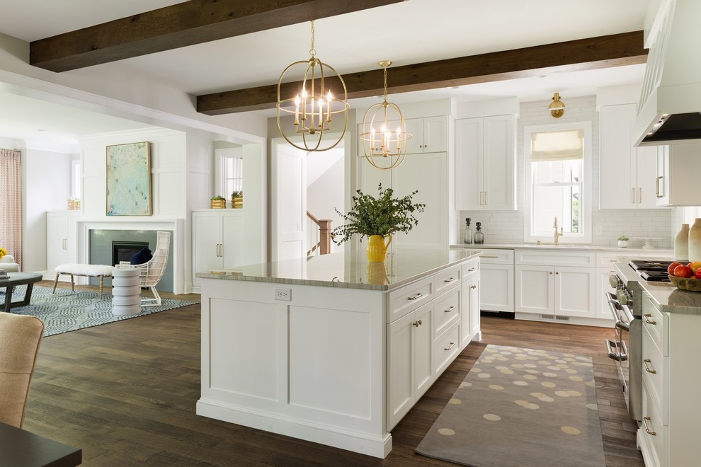 Maritim inredning av ett stort grå grått kök, med en undermonterad diskho, skåp i shakerstil, vita skåp, bänkskiva i kvartsit, vitt stänkskydd, stänkskydd i keramik, rostfria vitvaror, mellanmörkt trägolv, en köksö och brunt golv