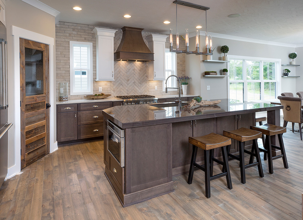 Example of a transitional galley medium tone wood floor and brown floor kitchen design in Columbus with an undermount sink, shaker cabinets, medium tone wood cabinets, beige backsplash, an island and brown countertops