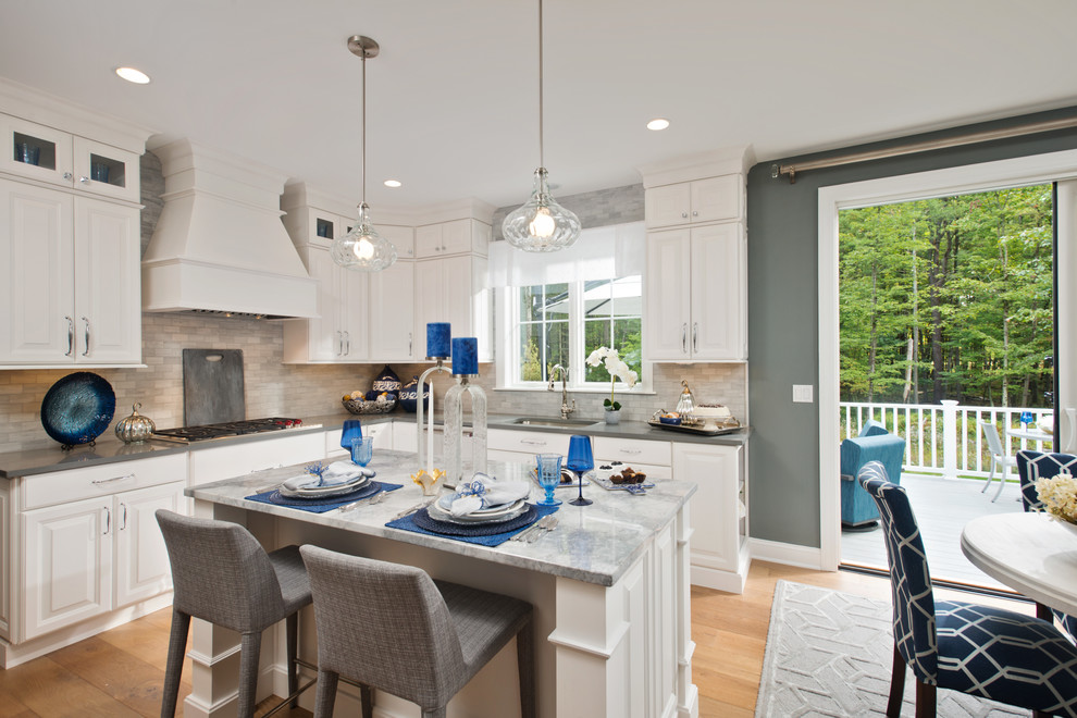 Beach style u-shaped medium tone wood floor eat-in kitchen photo in New York with an undermount sink, white cabinets, concrete countertops, gray backsplash, stainless steel appliances and an island