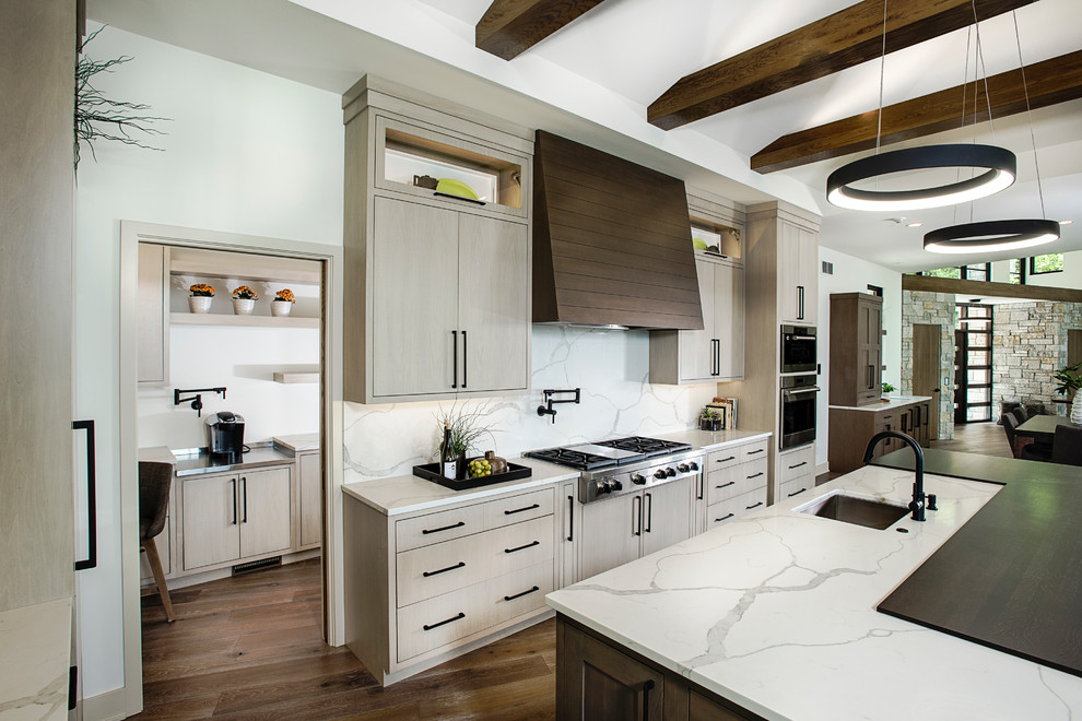 Bild på ett mycket stort funkis vit vitt kök, med en undermonterad diskho, släta luckor, skåp i ljust trä, vitt stänkskydd, stänkskydd i marmor, rostfria vitvaror, en köksö, brunt golv, bänkskiva i kvartsit och mörkt trägolv