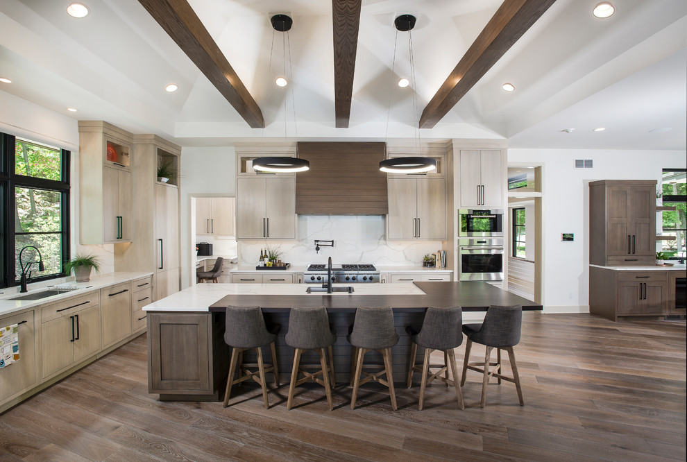 Design ideas for an expansive modern l-shaped open plan kitchen in Grand Rapids with a submerged sink, flat-panel cabinets, light wood cabinets, white splashback, marble splashback, stainless steel appliances, an island, brown floors, quartz worktops, dark hardwood flooring and white worktops.