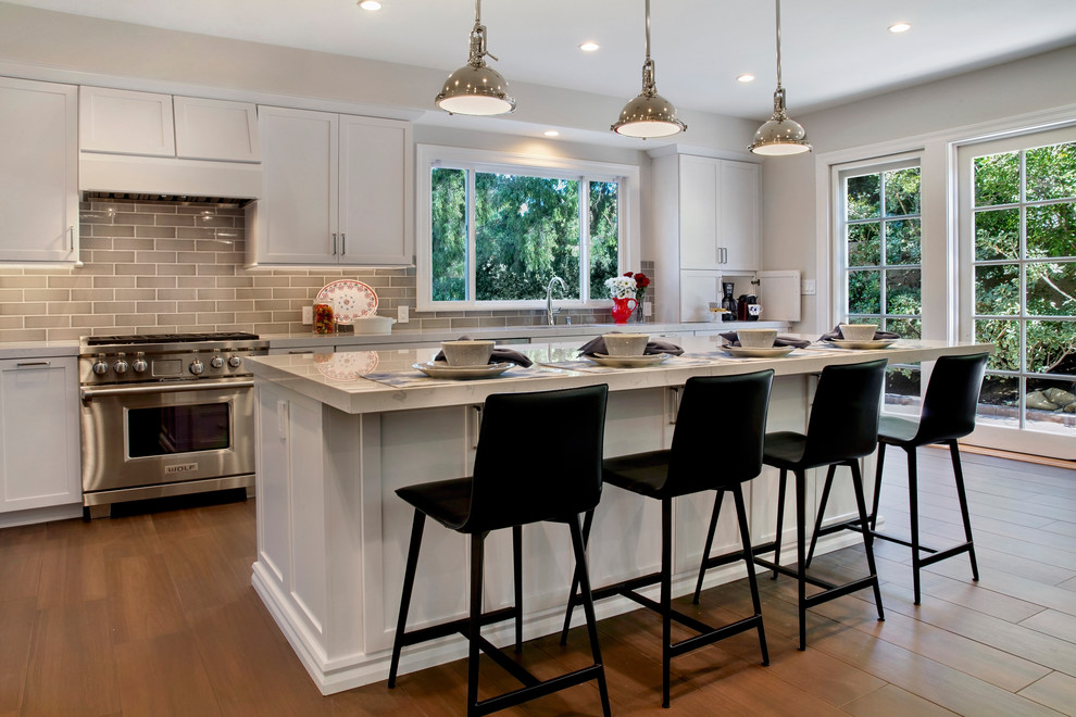 Inspiration for a large contemporary l-shaped porcelain tile and brown floor kitchen remodel in Orange County with a single-bowl sink, shaker cabinets, white cabinets, quartz countertops, gray backsplash, ceramic backsplash, stainless steel appliances and white countertops