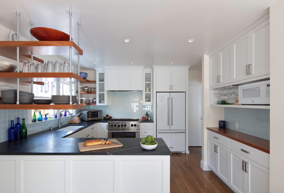 This is an example of a medium sized traditional u-shaped kitchen/diner in San Francisco with shaker cabinets, a breakfast bar, a submerged sink, white cabinets, blue splashback, stainless steel appliances, medium hardwood flooring, brown floors, grey worktops, soapstone worktops and glass tiled splashback.