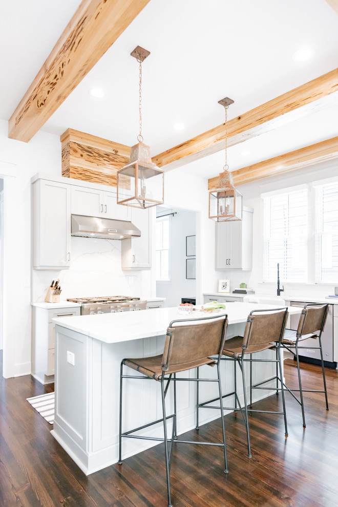 Bild på ett mellanstort lantligt vit vitt l-kök, med skåp i shakerstil, grå skåp, en köksö, en rustik diskho, vitt stänkskydd, stänkskydd i sten, rostfria vitvaror, mörkt trägolv och brunt golv