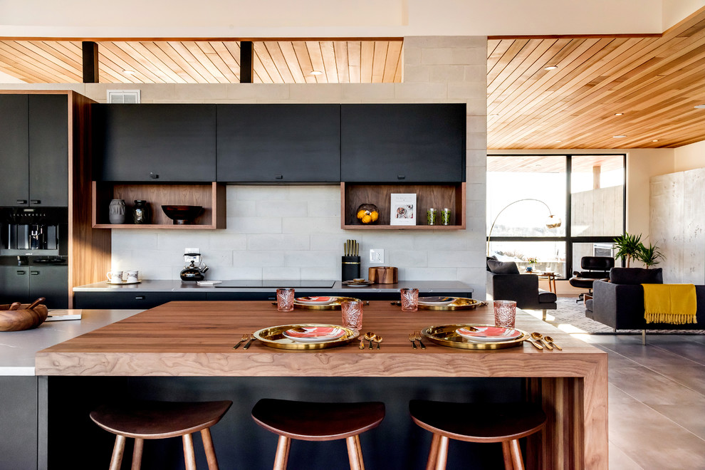 Bild på ett stort retro grå grått kök, med en undermonterad diskho, släta luckor, svarta skåp, bänkskiva i kvartsit, grått stänkskydd, stänkskydd i stenkakel, integrerade vitvaror, klinkergolv i keramik, en köksö och grått golv