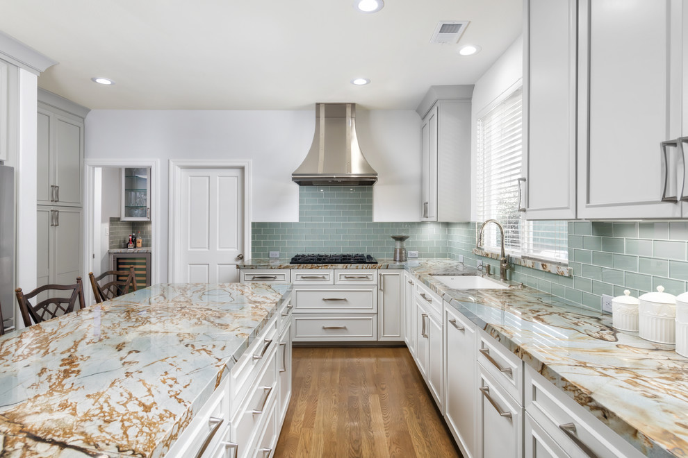 Elegant l-shaped medium tone wood floor kitchen photo in San Francisco with an undermount sink, recessed-panel cabinets, green backsplash, subway tile backsplash, an island, multicolored countertops and white cabinets