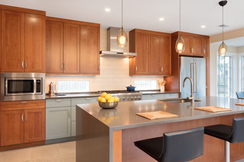 Diseño de cocina actual con salpicadero blanco, salpicadero de azulejos tipo metro, electrodomésticos de acero inoxidable y una isla