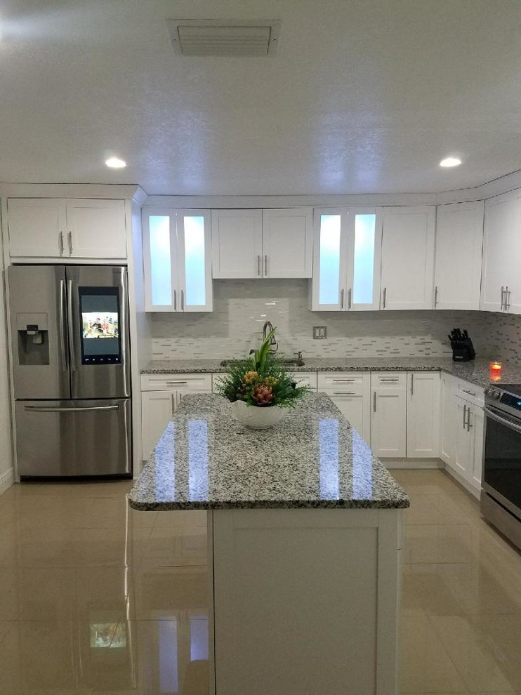 Modern inredning av ett stort grå grått kök, med en dubbel diskho, släta luckor, vita skåp, granitbänkskiva, flerfärgad stänkskydd, stänkskydd i cementkakel, rostfria vitvaror, cementgolv, en köksö och brunt golv