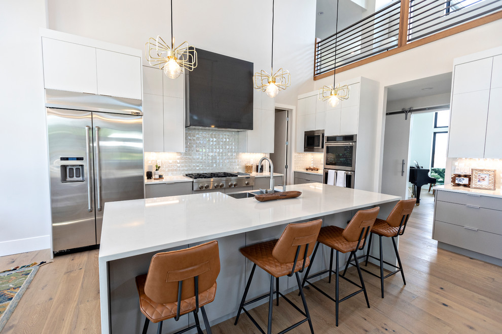 Eat-in kitchen - contemporary l-shaped medium tone wood floor and brown floor eat-in kitchen idea in Salt Lake City with a farmhouse sink, white backsplash, an island, flat-panel cabinets, white cabinets, stainless steel appliances and white countertops