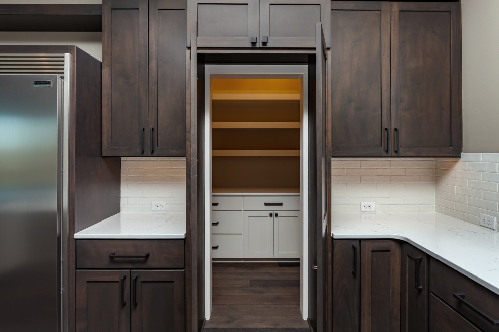 This is an example of a classic u-shaped kitchen pantry in Other with a submerged sink, shaker cabinets, medium wood cabinets, engineered stone countertops, white splashback, ceramic splashback, stainless steel appliances, carpet, brown floors and white worktops.