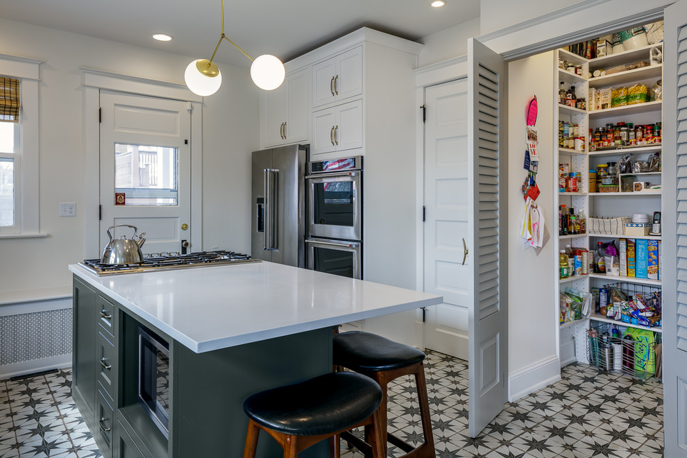 Cette image montre une cuisine américaine rustique avec un placard à porte affleurante, des portes de placards vertess, un plan de travail en quartz modifié, un électroménager en acier inoxydable, îlot et un plan de travail blanc.