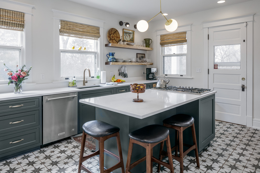 Photo of a farmhouse kitchen in Other with beaded cabinets, green cabinets, engineered stone countertops, stainless steel appliances, an island, white worktops, a submerged sink and multi-coloured floors.