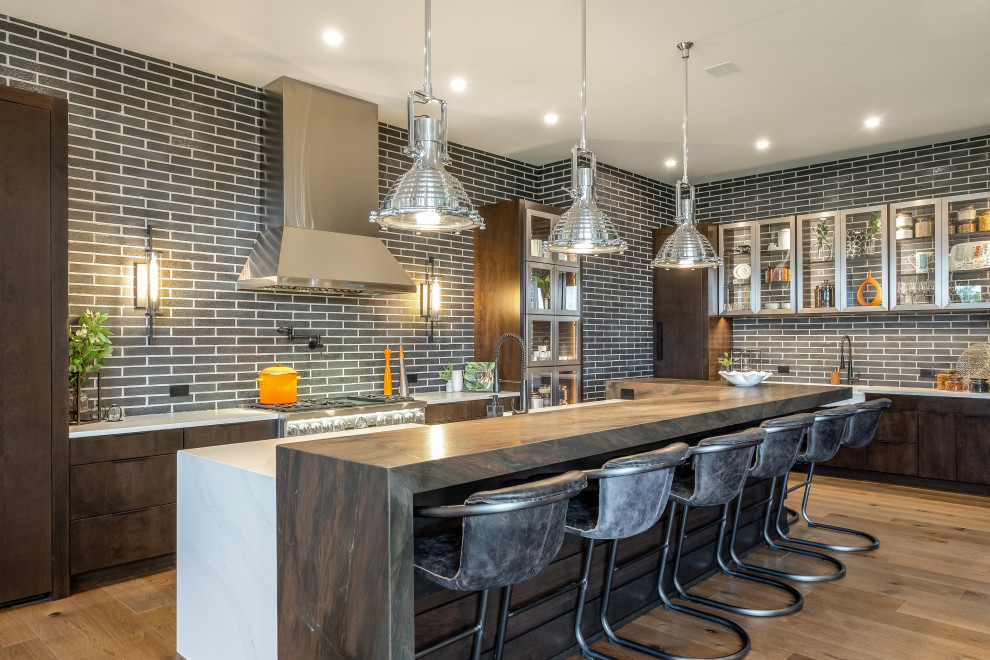 Example of a large trendy l-shaped open concept kitchen design in Other with a farmhouse sink, flat-panel cabinets, medium tone wood cabinets, quartz countertops, gray backsplash, brick backsplash, stainless steel appliances, an island and white countertops
