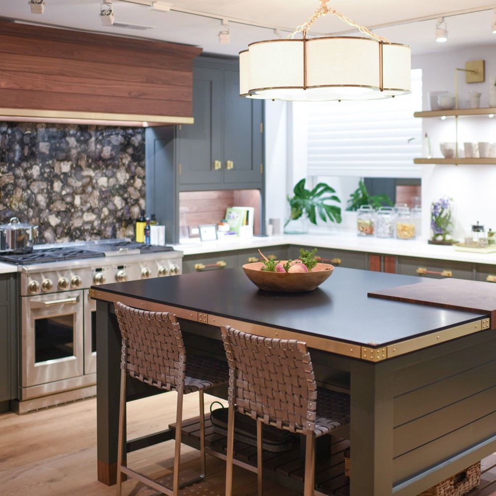 Foto på ett eklektiskt svart kök, med gröna skåp, rostfria vitvaror, ljust trägolv och en köksö