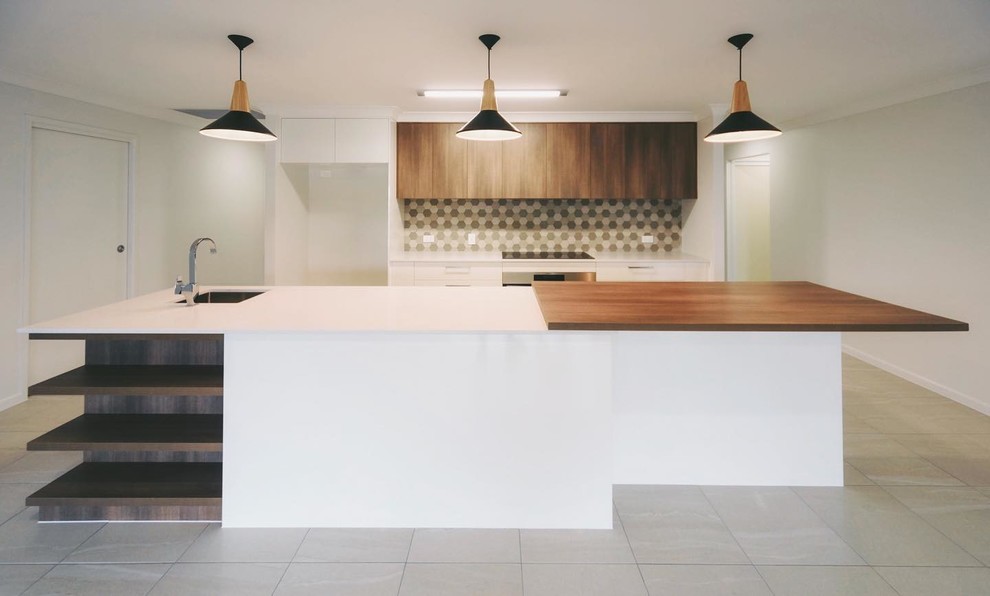 Cette image montre une cuisine minimaliste en bois brun avec un évier encastré, une crédence en mosaïque, un électroménager en acier inoxydable et îlot.