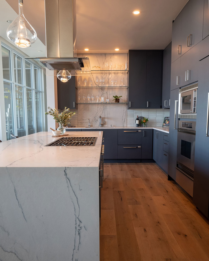 Inspiration for a mid-sized modern l-shaped medium tone wood floor open concept kitchen remodel in Portland with an undermount sink, flat-panel cabinets, blue cabinets, quartzite countertops, white backsplash, glass tile backsplash, stainless steel appliances, an island and white countertops