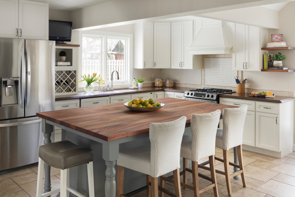 Klassisk inredning av ett mellanstort brun brunt kök, med en undermonterad diskho, luckor med infälld panel, vita skåp, träbänkskiva, vitt stänkskydd, stänkskydd i marmor, rostfria vitvaror, klinkergolv i porslin, en köksö och brunt golv