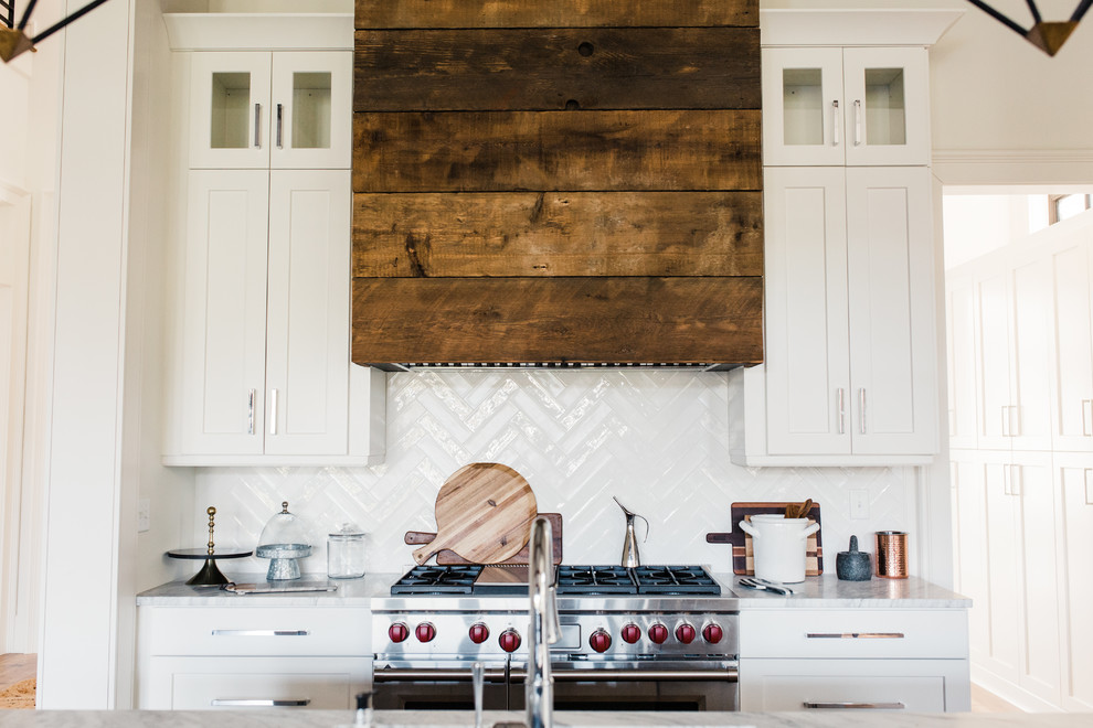 Klassische Wohnküche in L-Form mit Schrankfronten mit vertiefter Füllung, weißen Schränken, Küchenrückwand in Weiß, Küchengeräten aus Edelstahl, braunem Holzboden, Kücheninsel, braunem Boden und weißer Arbeitsplatte in Charleston