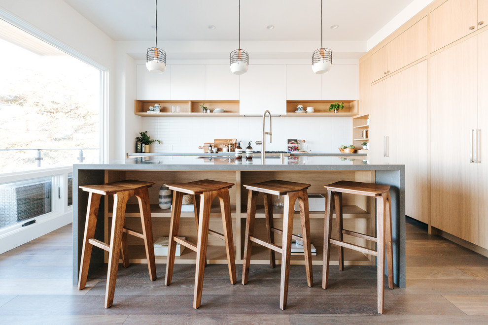 Kleine Moderne Wohnküche in L-Form mit flächenbündigen Schrankfronten, weißen Schränken, Küchenrückwand in Weiß, braunem Holzboden, Kücheninsel, braunem Boden und grauer Arbeitsplatte in San Francisco