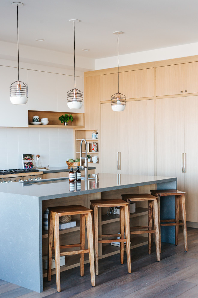 Kleine Moderne Küche in L-Form mit Unterbauwaschbecken, flächenbündigen Schrankfronten, hellen Holzschränken, Küchenrückwand in Weiß, braunem Holzboden, Kücheninsel, braunem Boden und grauer Arbeitsplatte in San Francisco